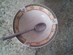 Pictured here is a dirty bowl and spoon with remnants of oatmeal.