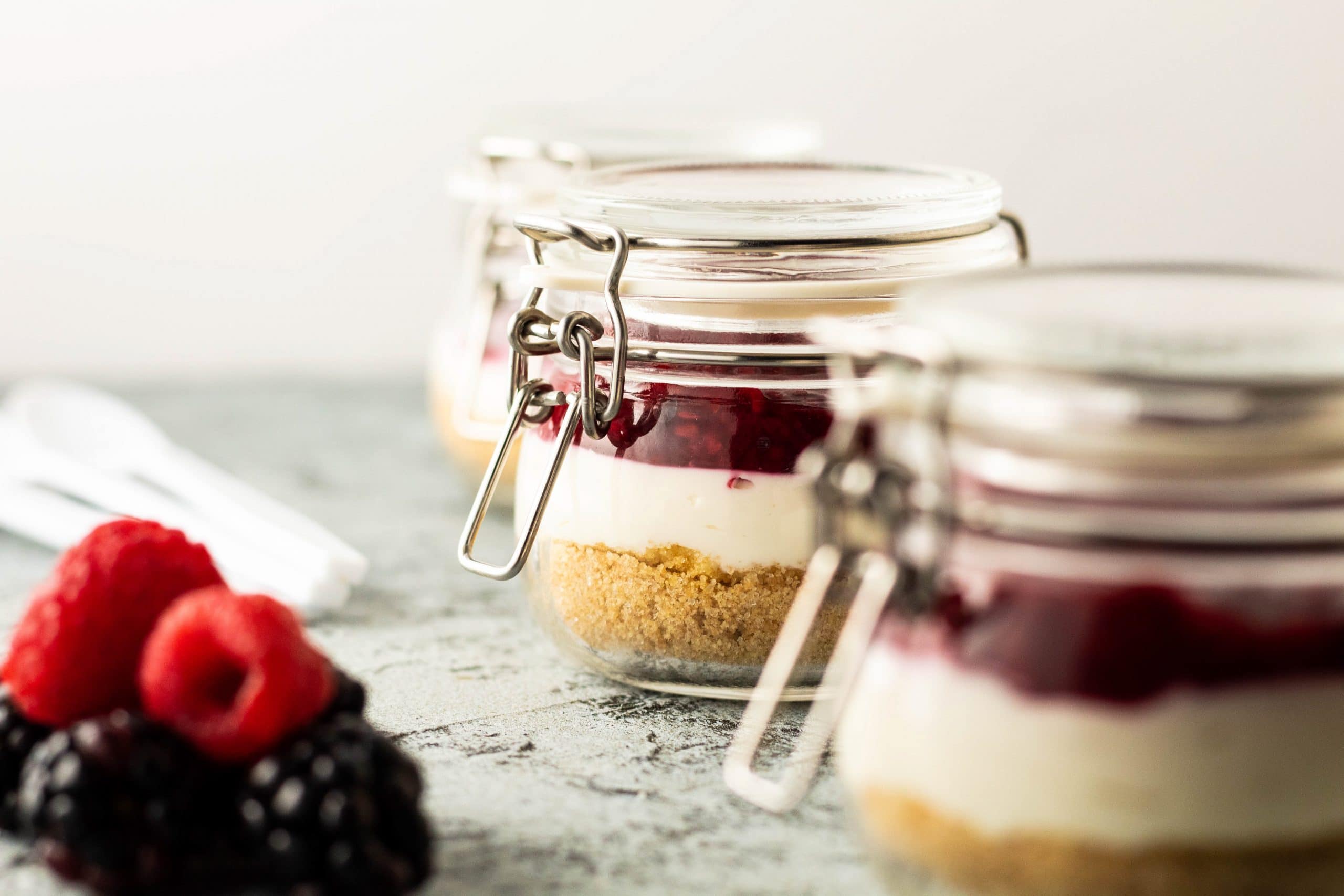 Berry cheesecake jars with graham crust, creamy filling, and berry compote layered in glass jars.