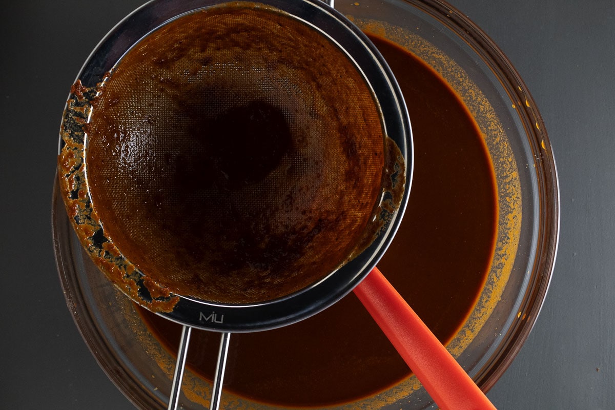 This image shows us straining the birria chile sauce.