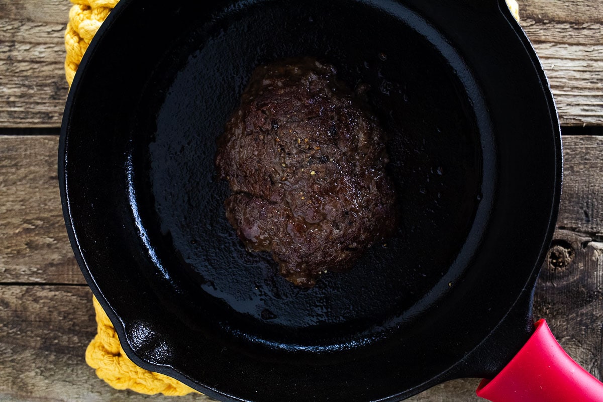 This is an image of the smash burger in a cast iron pan. 