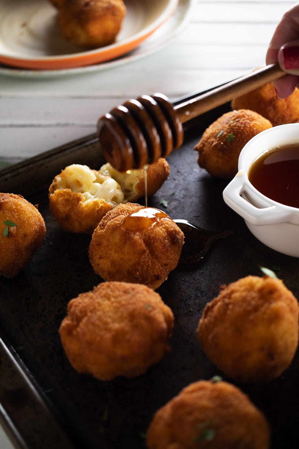 This is an image of our hot honey mac and cheese balls with a honey drip.