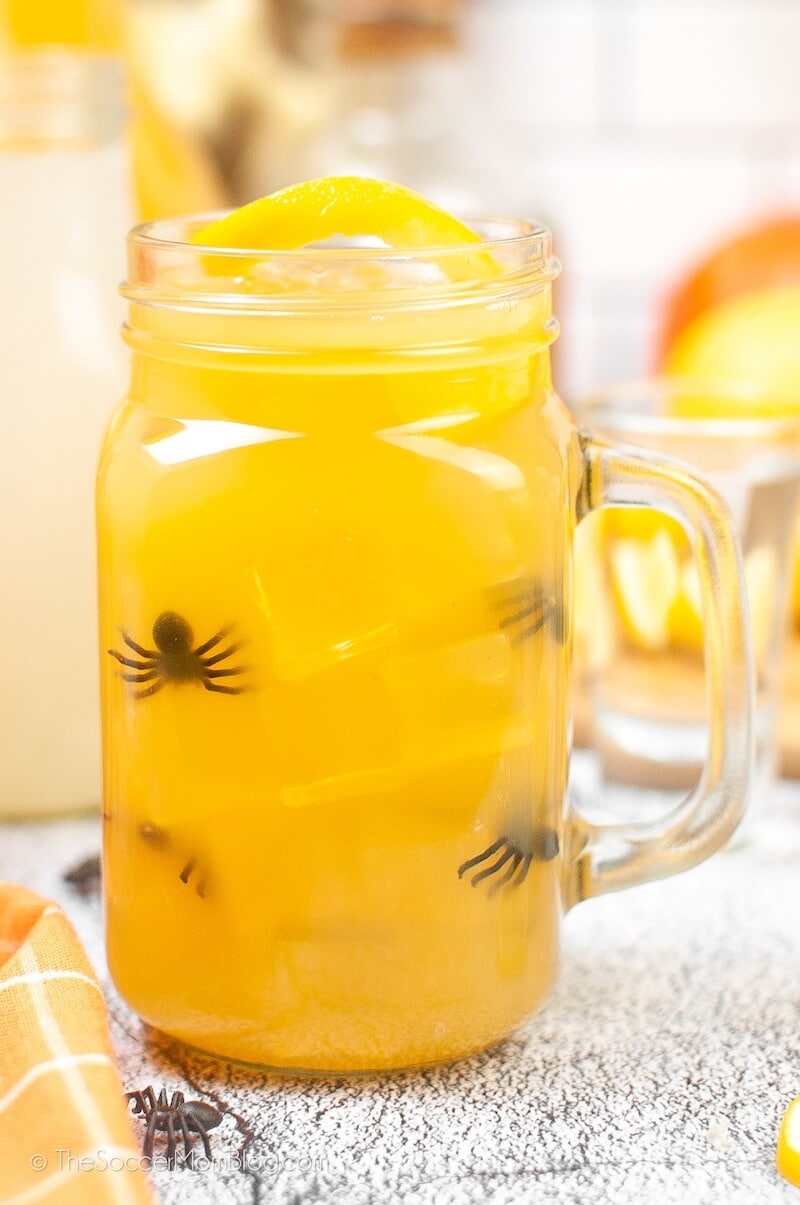 Orange alcoholic drink with toy spiders in a glass jar.