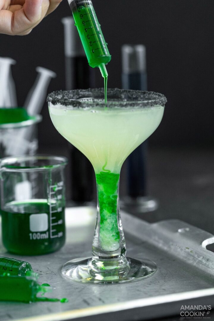 Margaritas with black salt rim, and syringe filled green corn syrup mixture.