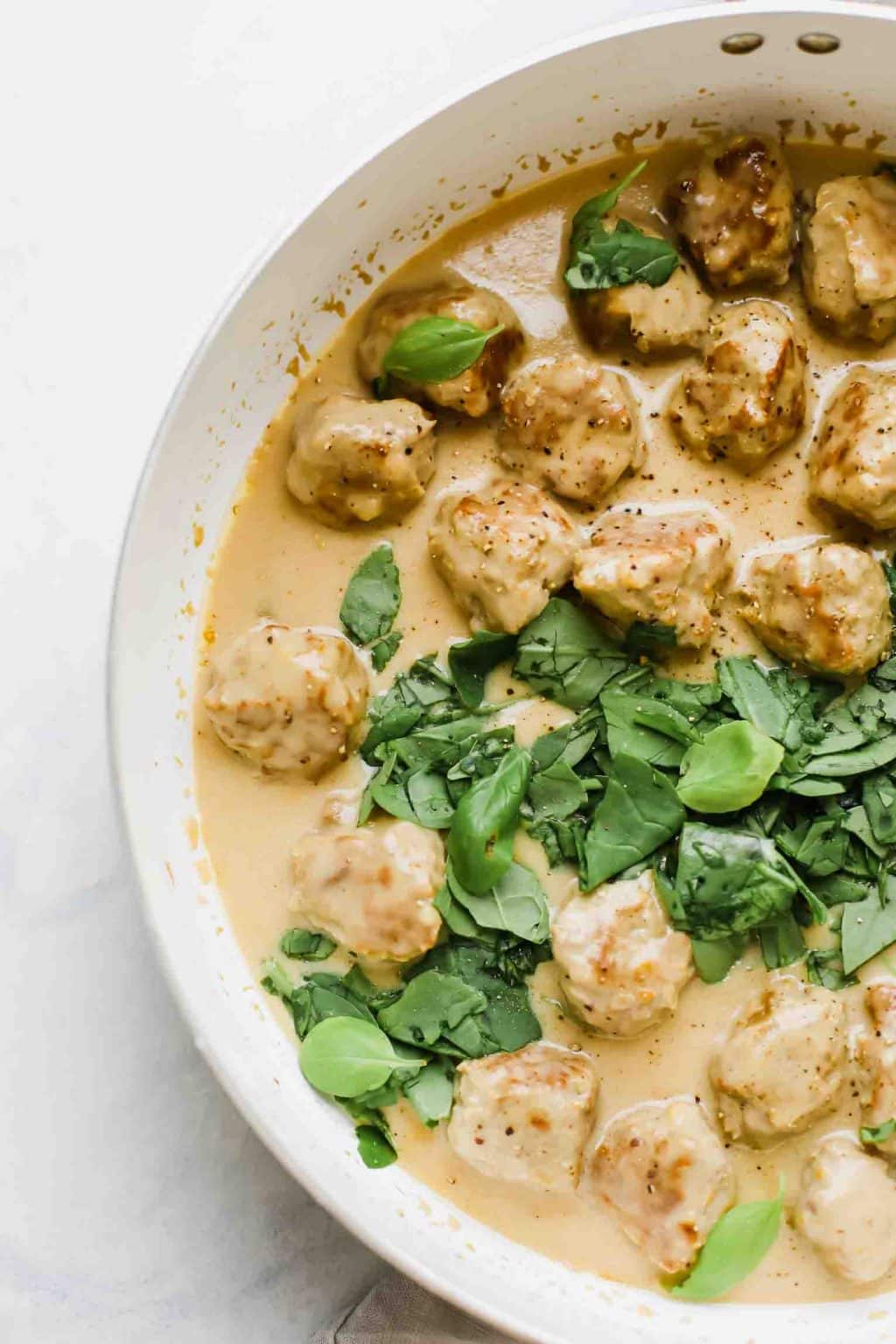 Healthy turkey Swedish meatballs with herbs in a pan.