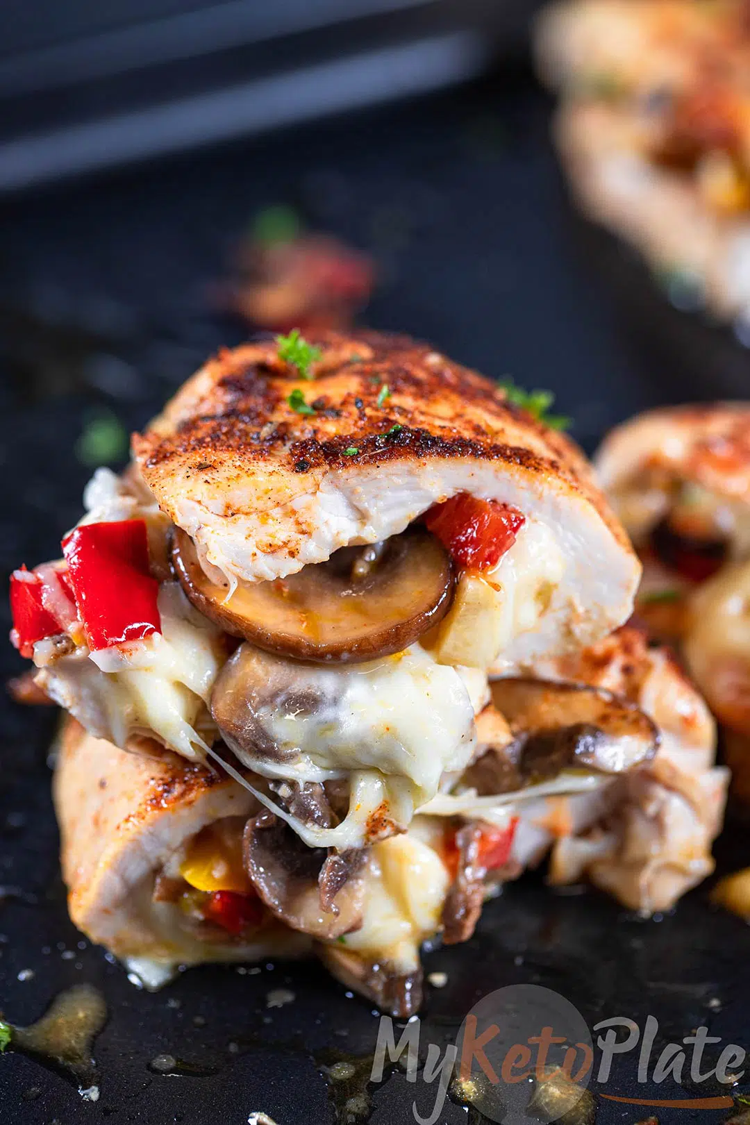 Cajun seasoned chicken breast stuffed with mozzarella, mushrooms, bell peppers on dark background.