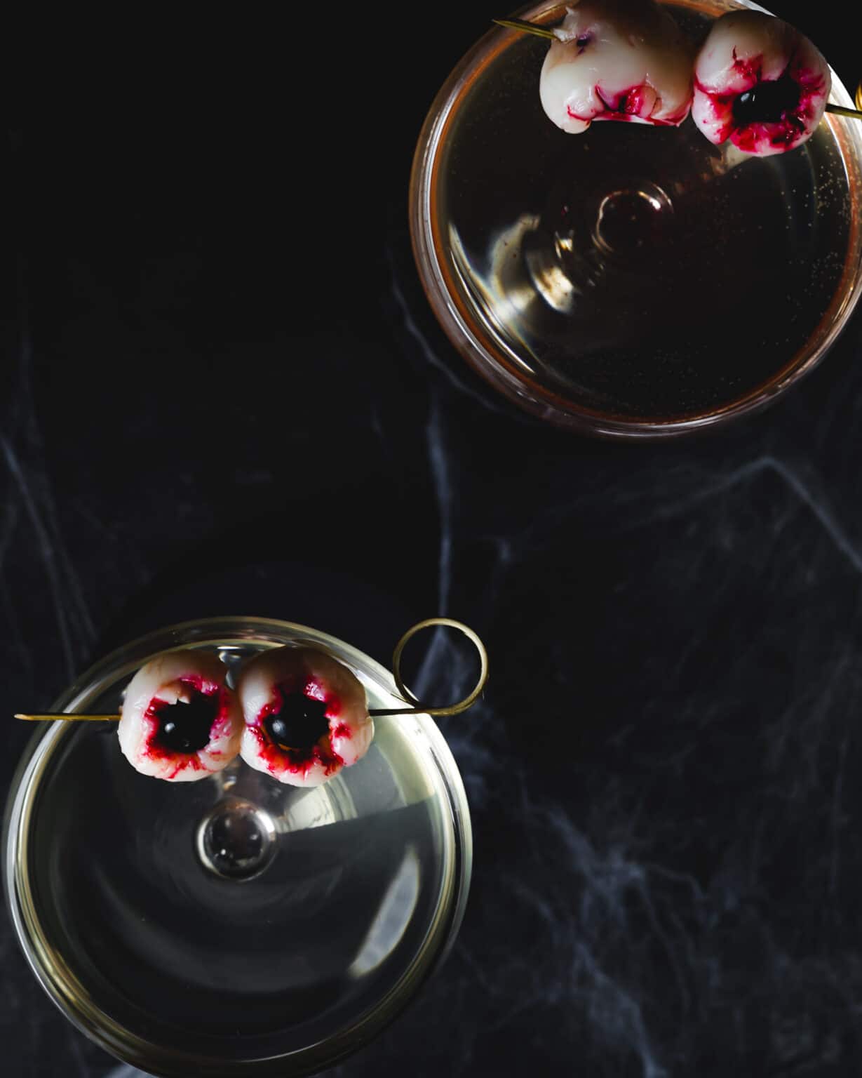 Overhead image of alcoholic beverage with fruit "eyeballs" on skewers.