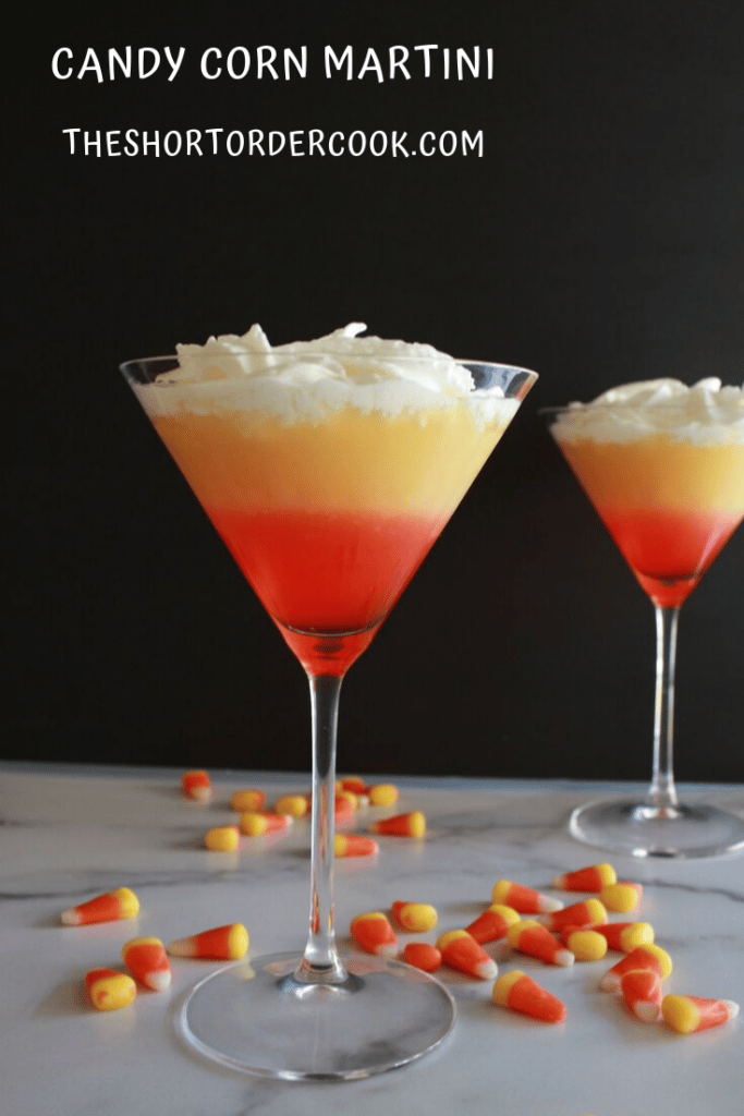 Multicolored cocktail drink with orange, yellow, and white at the top with dark background.