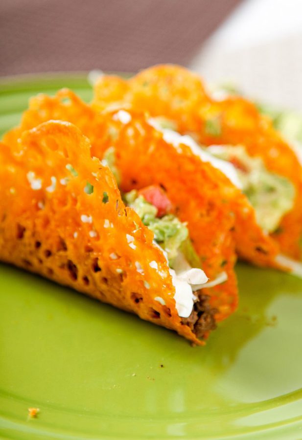 Taco shells made out of cheese on a green plate.