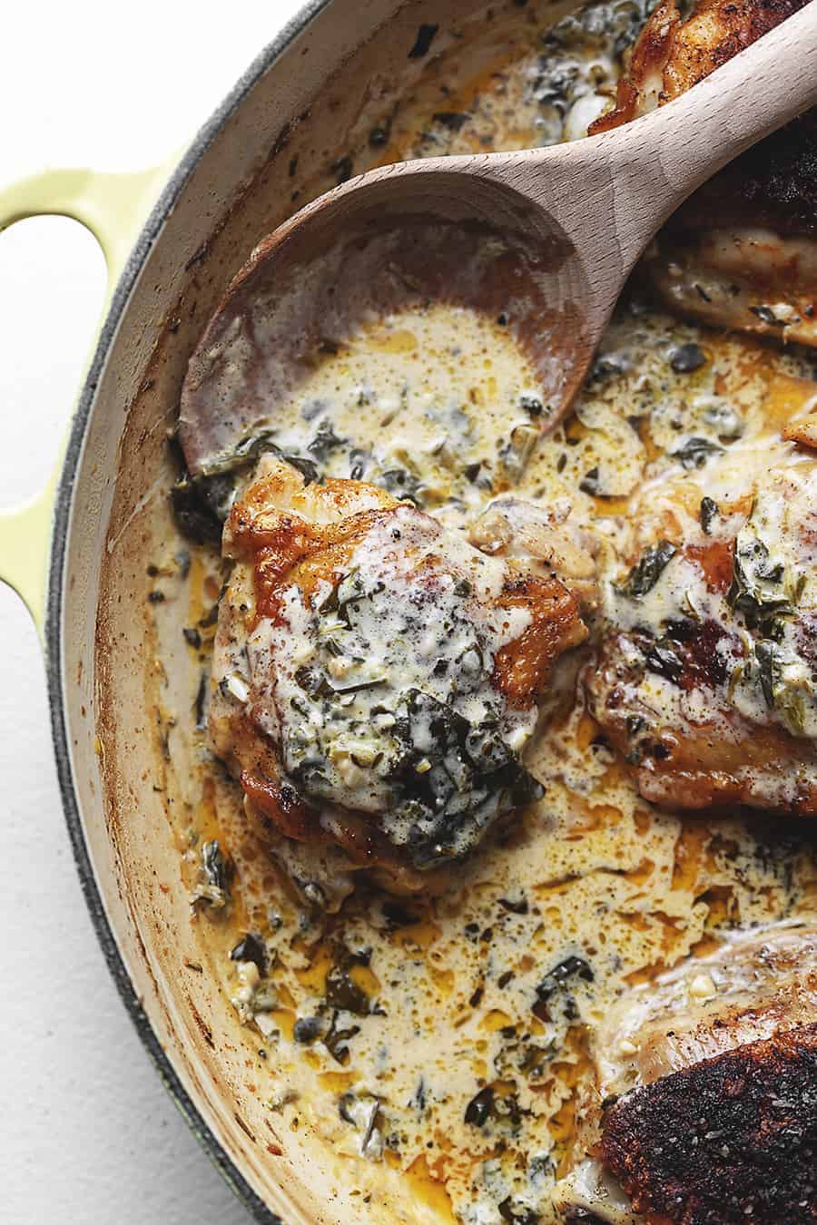 Creamy lemon chicken thighs in pan with wooden pan.