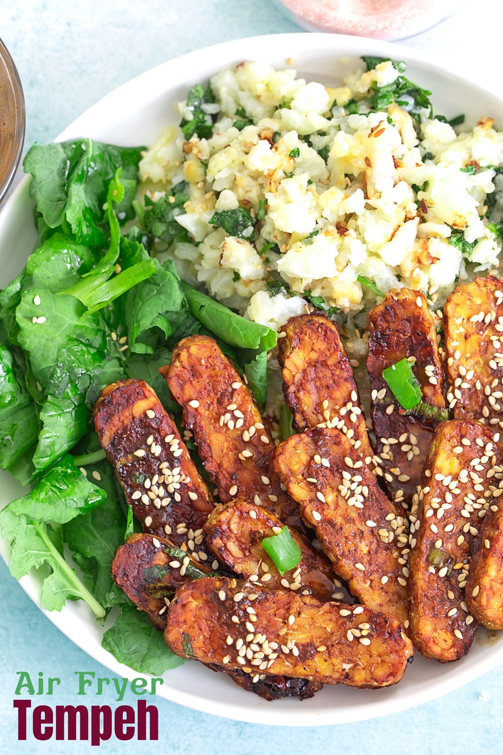 Air tempeh with vegetables in white bowl and blue background.