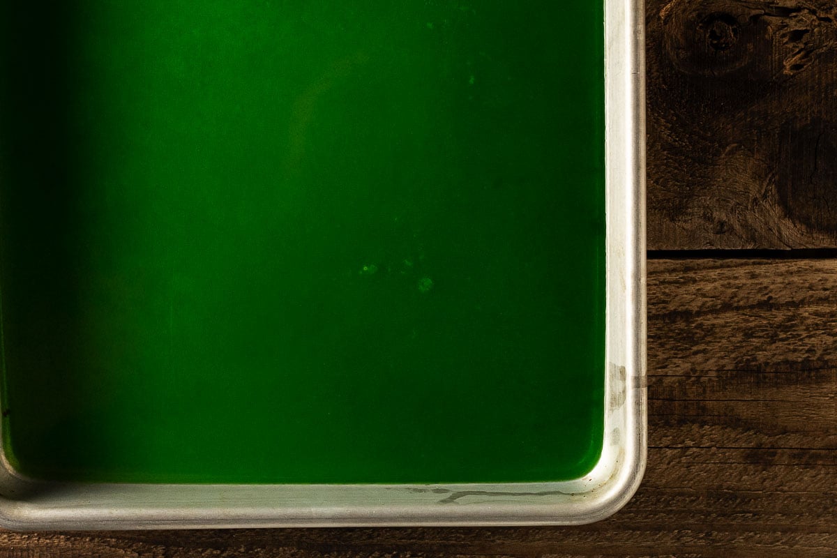 Green gelatin in pan on wooden background.