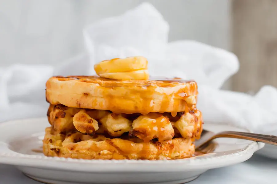 Keto protein chaffles with low carb syrup on a white plate.