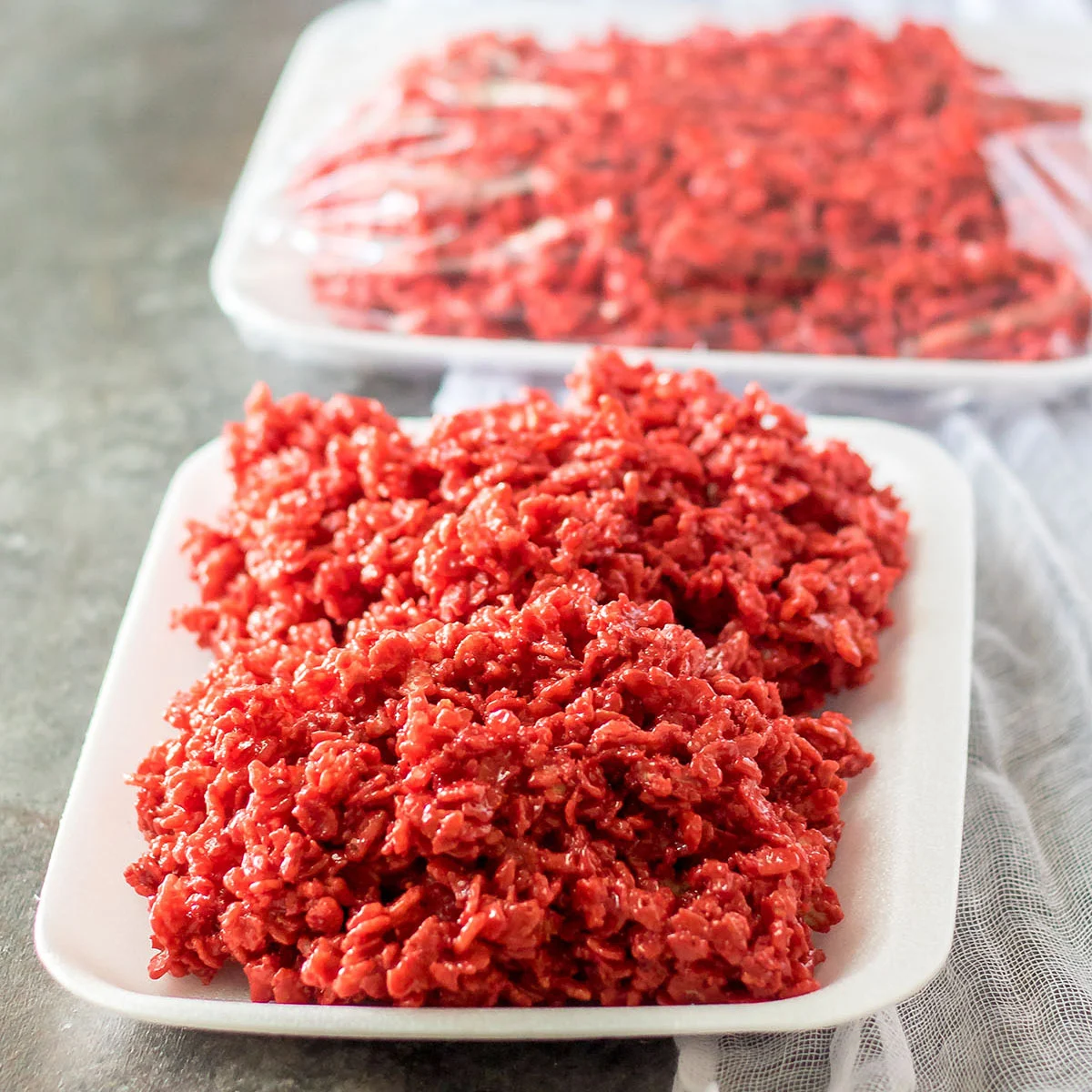 Red rice Krispies arranged to look like raw ground meat on a styrofoam tray.