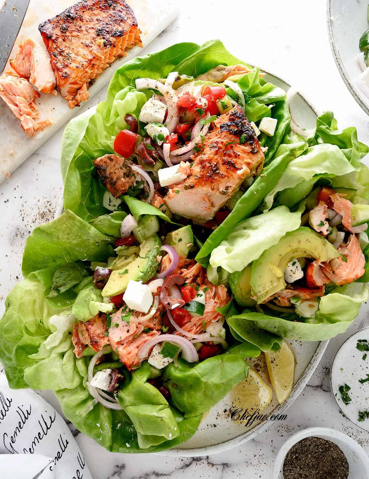Mediterranean salmon lettuce wraps on white plates.