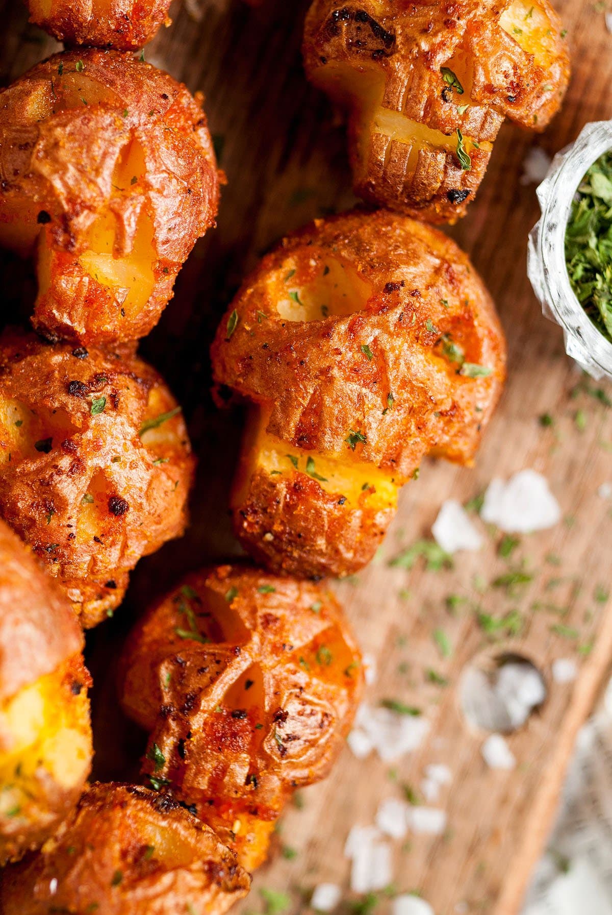 Potatoes carved into skulls with seasonings on skewers with wooden background.