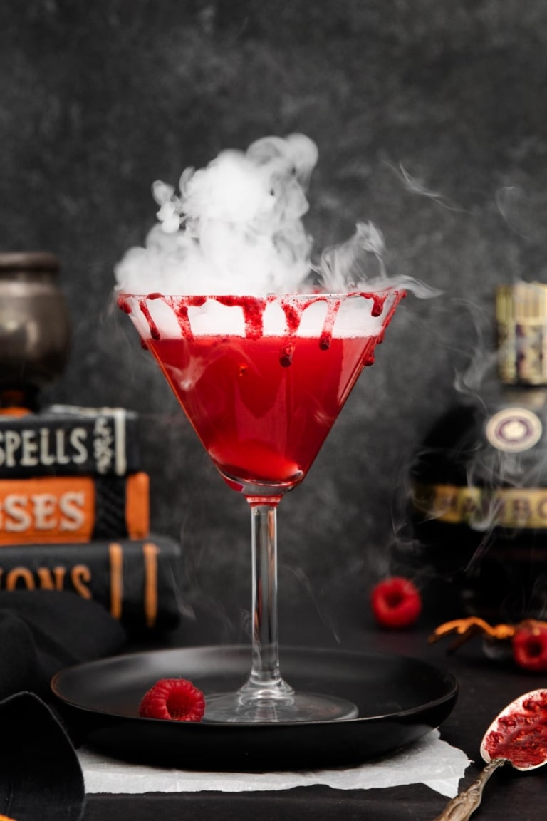 Red vampire's kiss cocktail in glass and with smoke emanating from it.