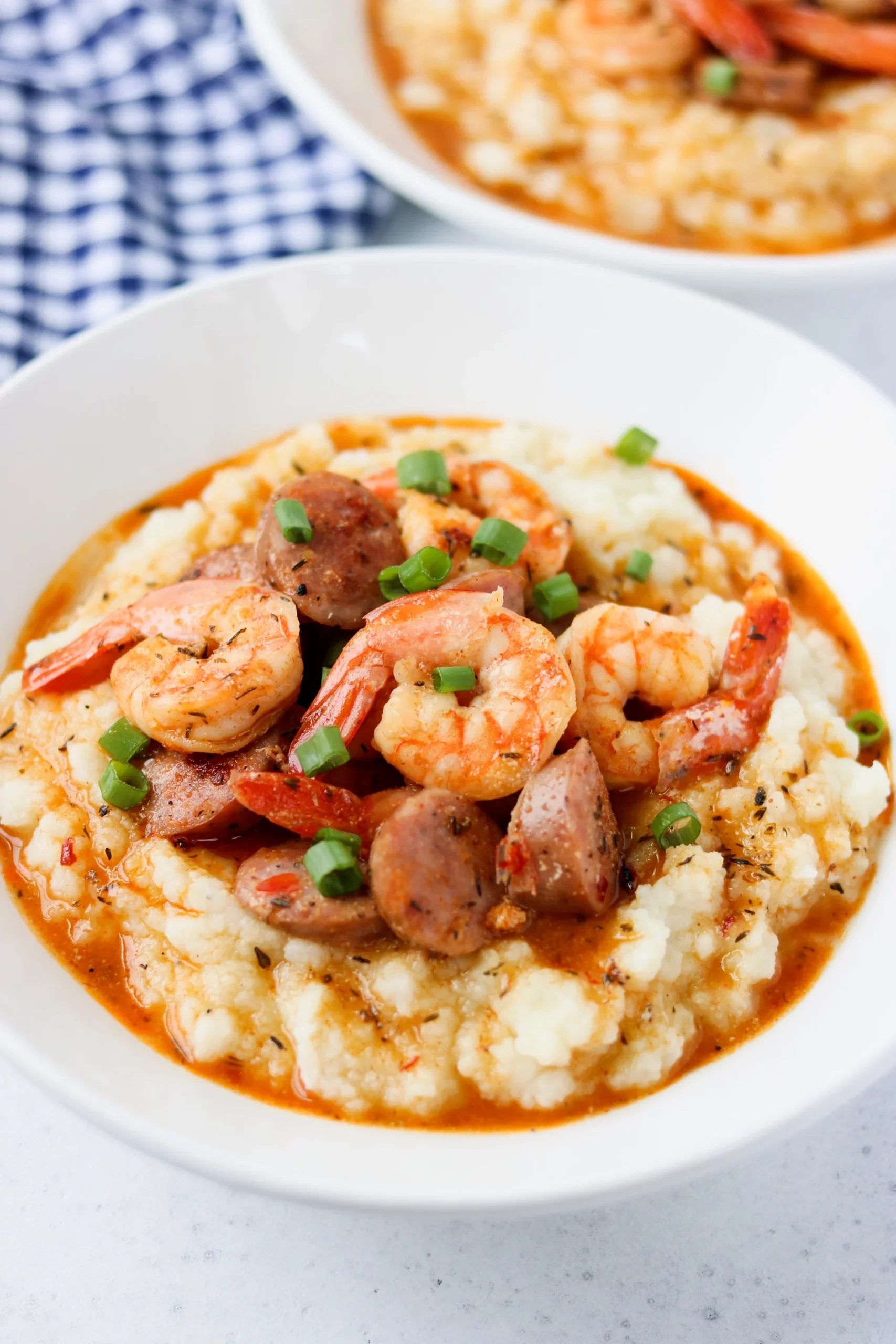 Keto shrimp and cauliflower grits in a bowl with checkered napkin in background.