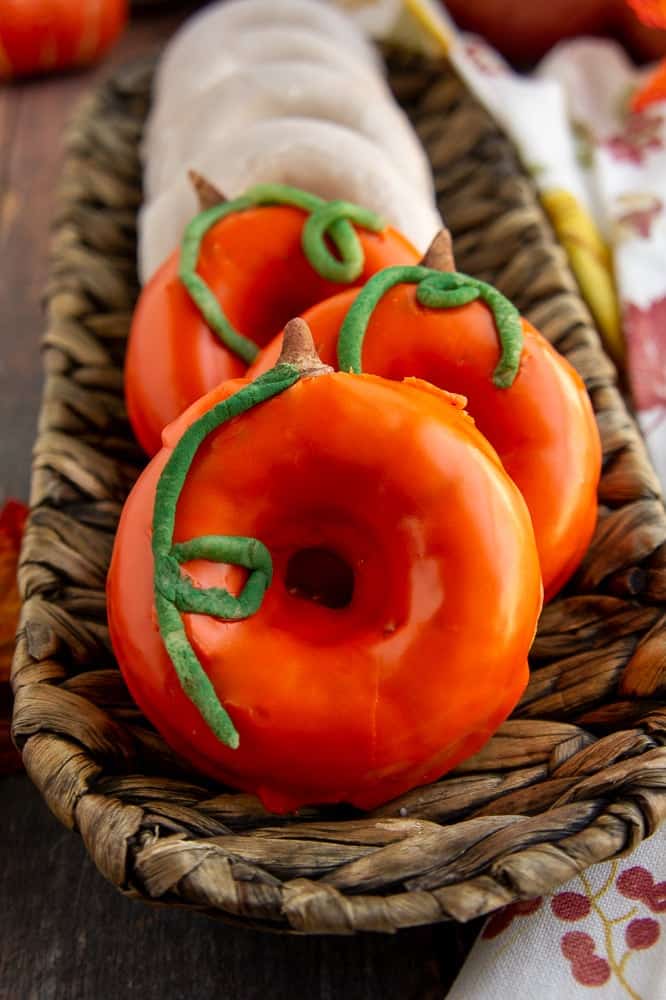 Baked decorated pumpkin donuts in a row.