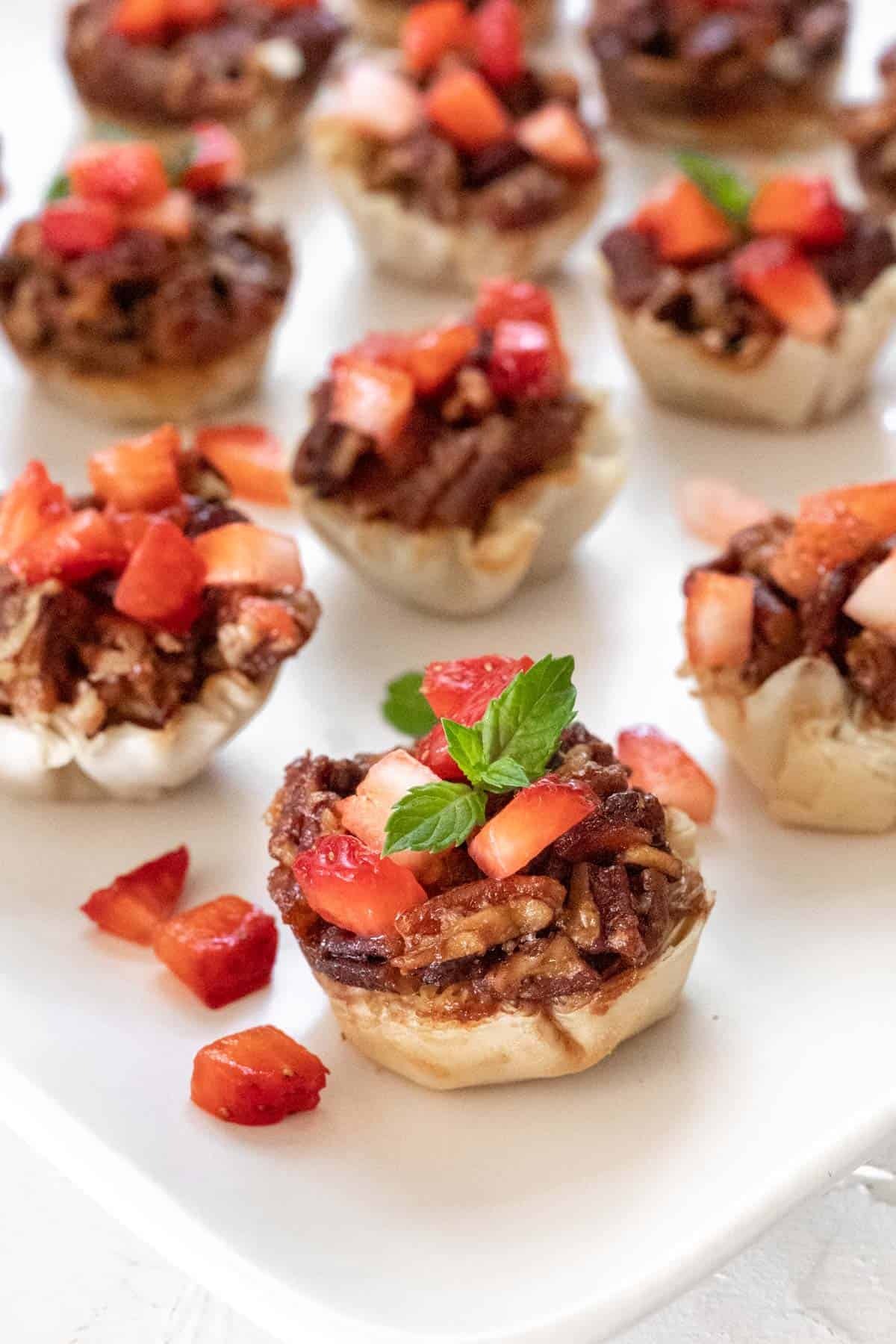 Bacon bourbon pecan brie bites on white platter.