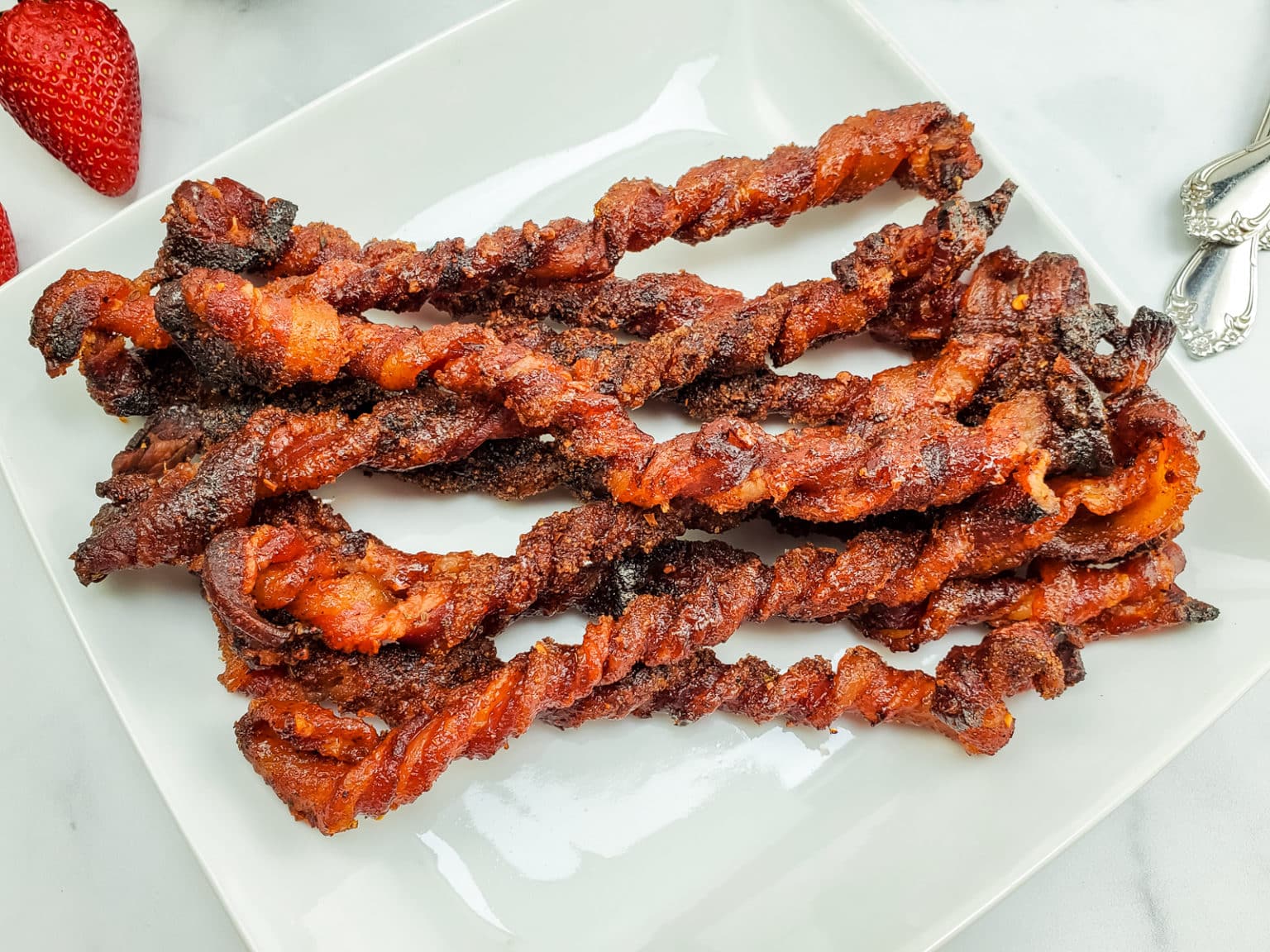 Candied twisted bacon on a white plate.