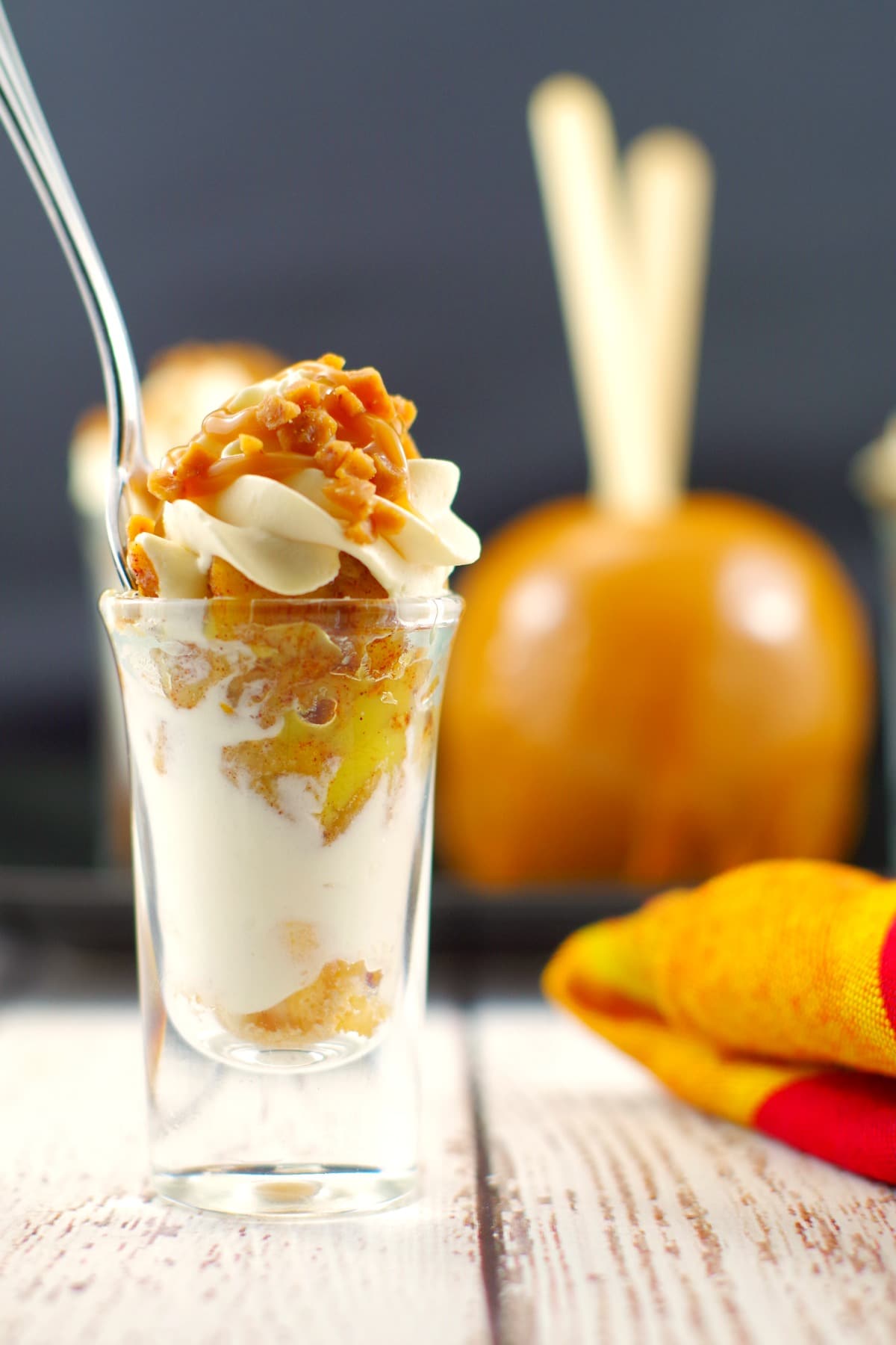 Close up of caramel apple betty shooter with caramel apple in the background.