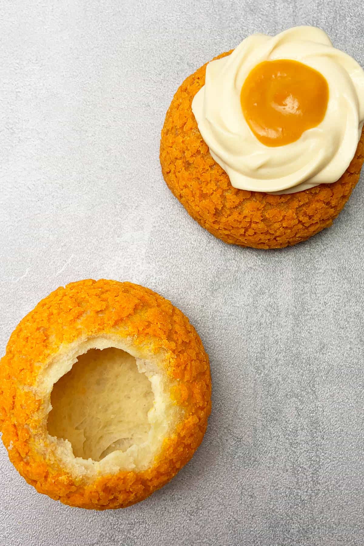 Empty pumpkin cream puff shell and pumpkin cream puff with filling on grey background.