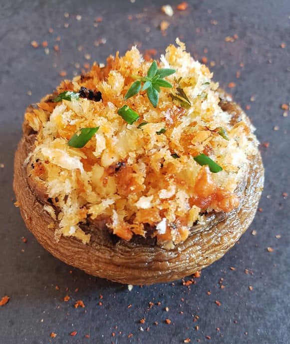 Air fryer stuffed mushrooms on a grey background.