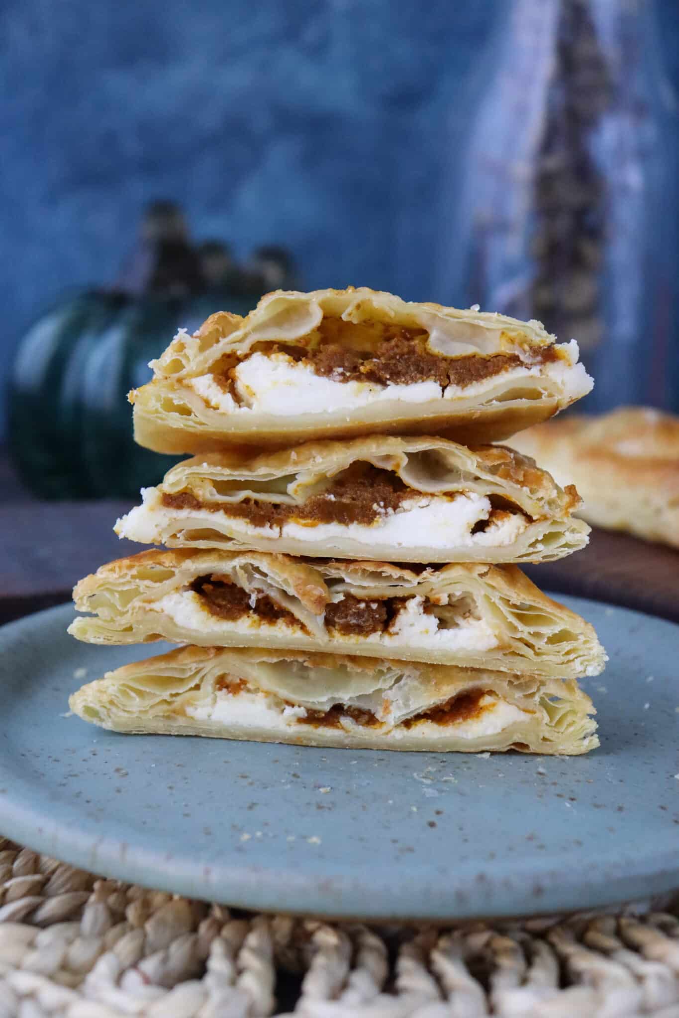 Pumpkin pie pastelitos stacked on a blue plate.