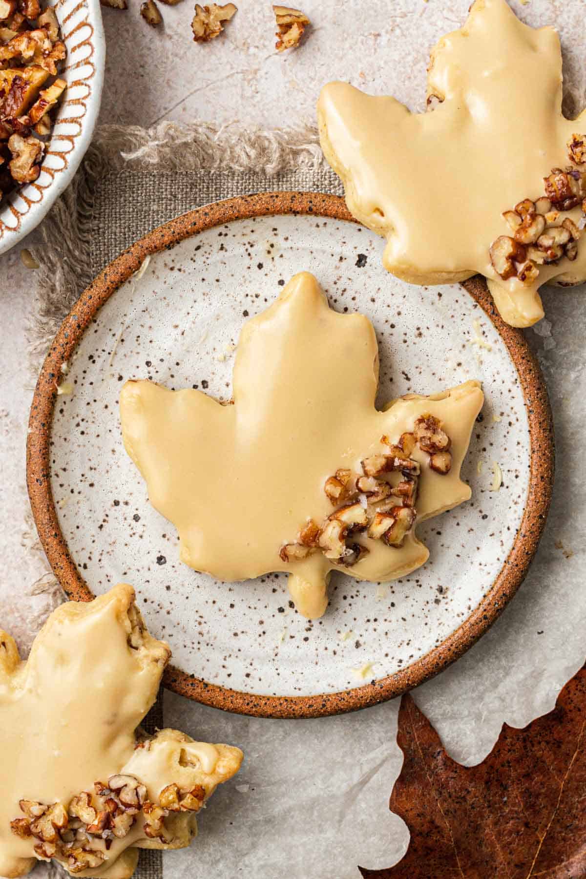 Leaf shaped glazed pecan shortbread cookies arranged on a plate.