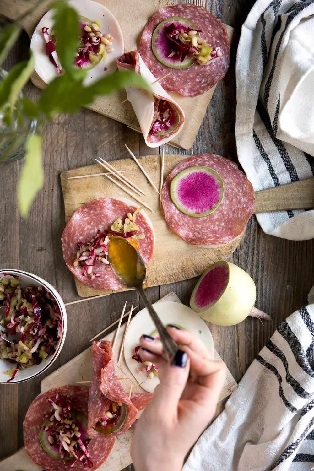 Soppressata and radish provolone cones with various ingredients and kitchen towel on wooden board.