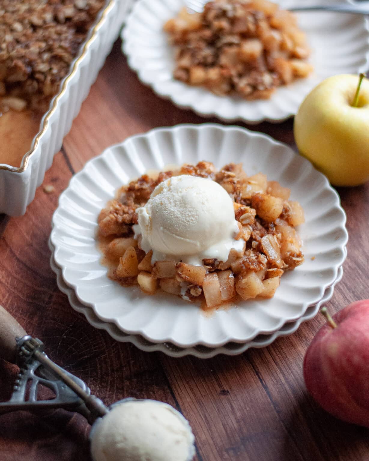 Apple crisp with scoop of ice cream on a white plate.