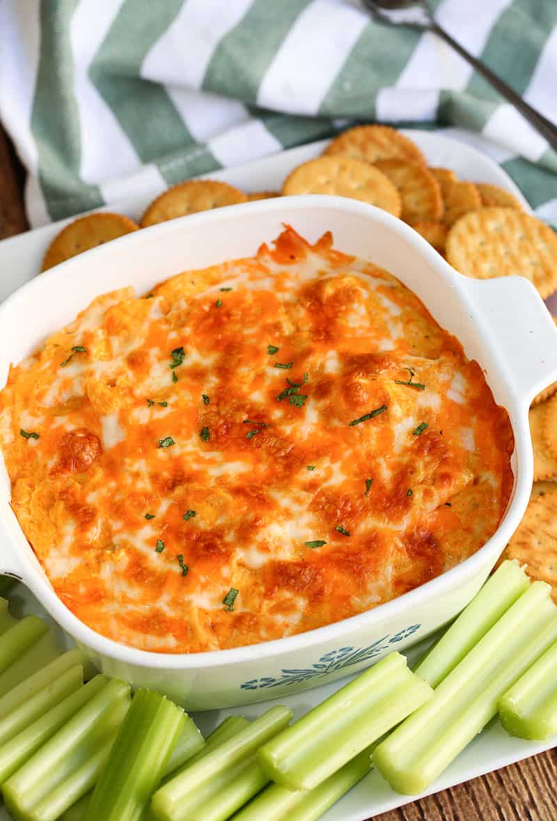 White baking dish with buffalo chicken dip and celery, and cracker dippers.