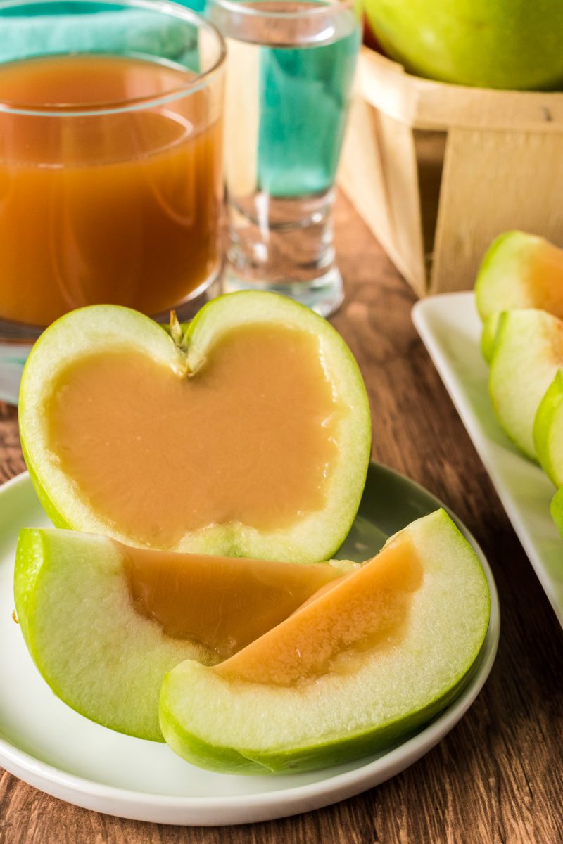 Cut caramel Jello shot inside Granny Smith apple on a plate.