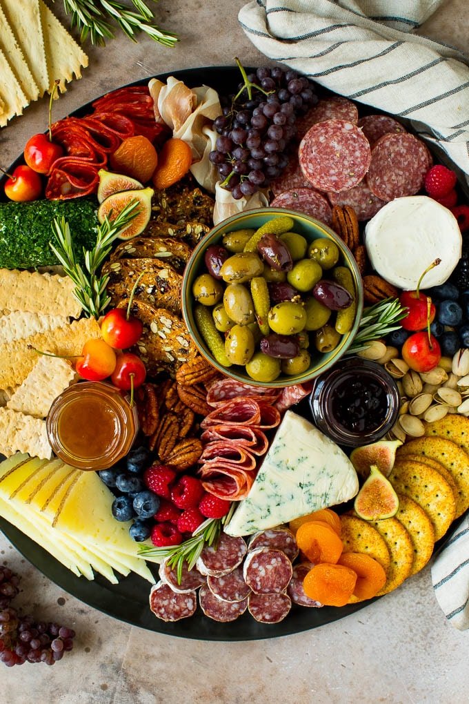 Charcuterie board with various meats, cheeses, fruits, and crackers on a tray.