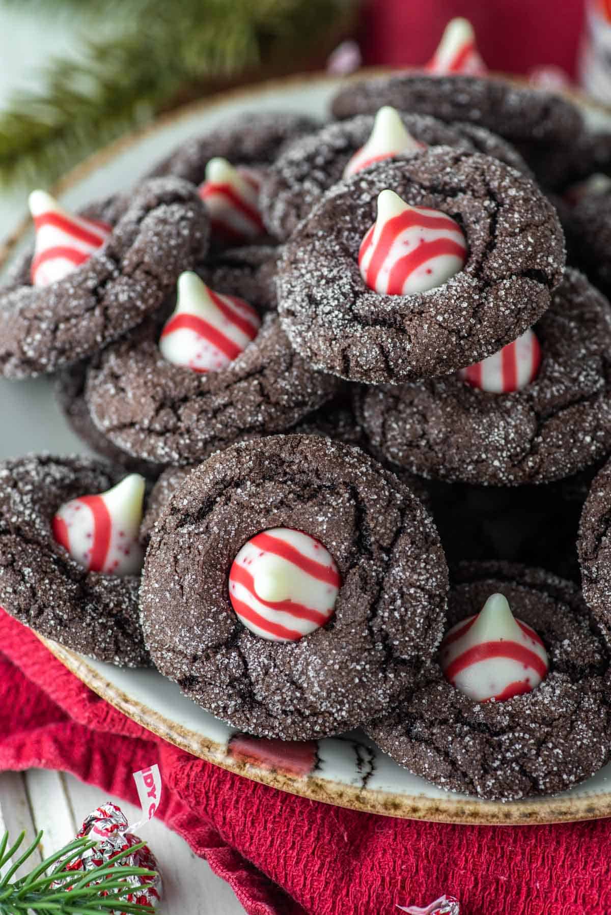 Bunch of chocolate cookies with peppermint candies in middle on a plate.