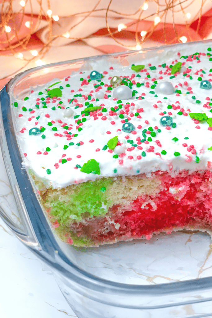 Colorful Christmas poke cake in a clear baking pan.