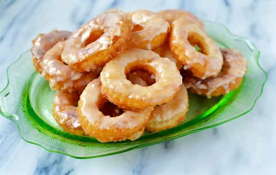 Bunch of puff pastry maple glazed donuts on a green plate.