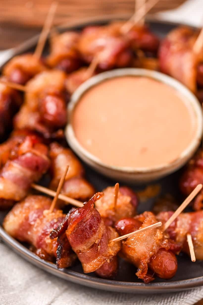Bacon wrapped little smokies on toothpicks on a dishcloth.
