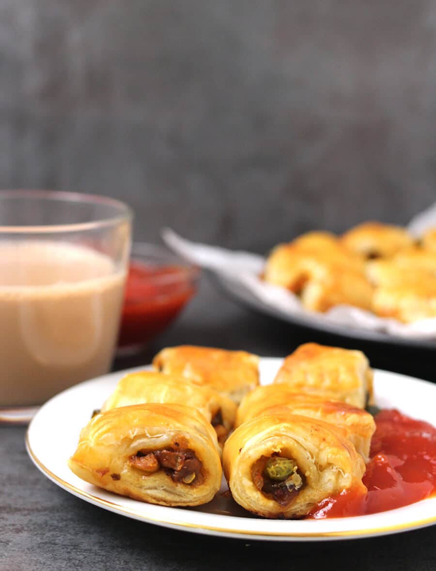 Veggie filled puff pastry bites on a plate with ketchup and chocolate milk in the background.