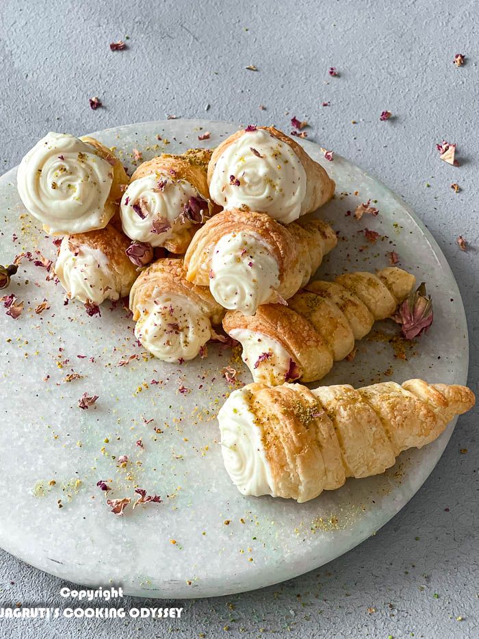 Puff pastry cream horns on a marble rotating tray.