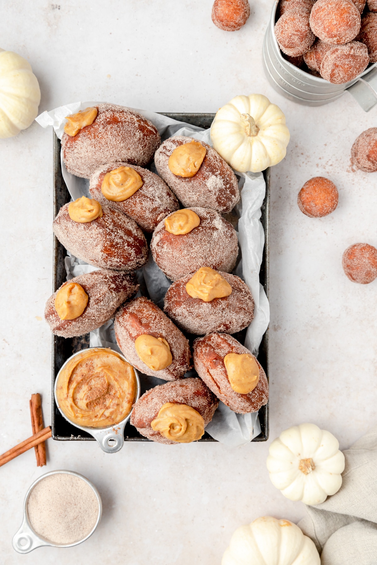 Pumpkin cream filled fried donuts in a pan with more in the background.