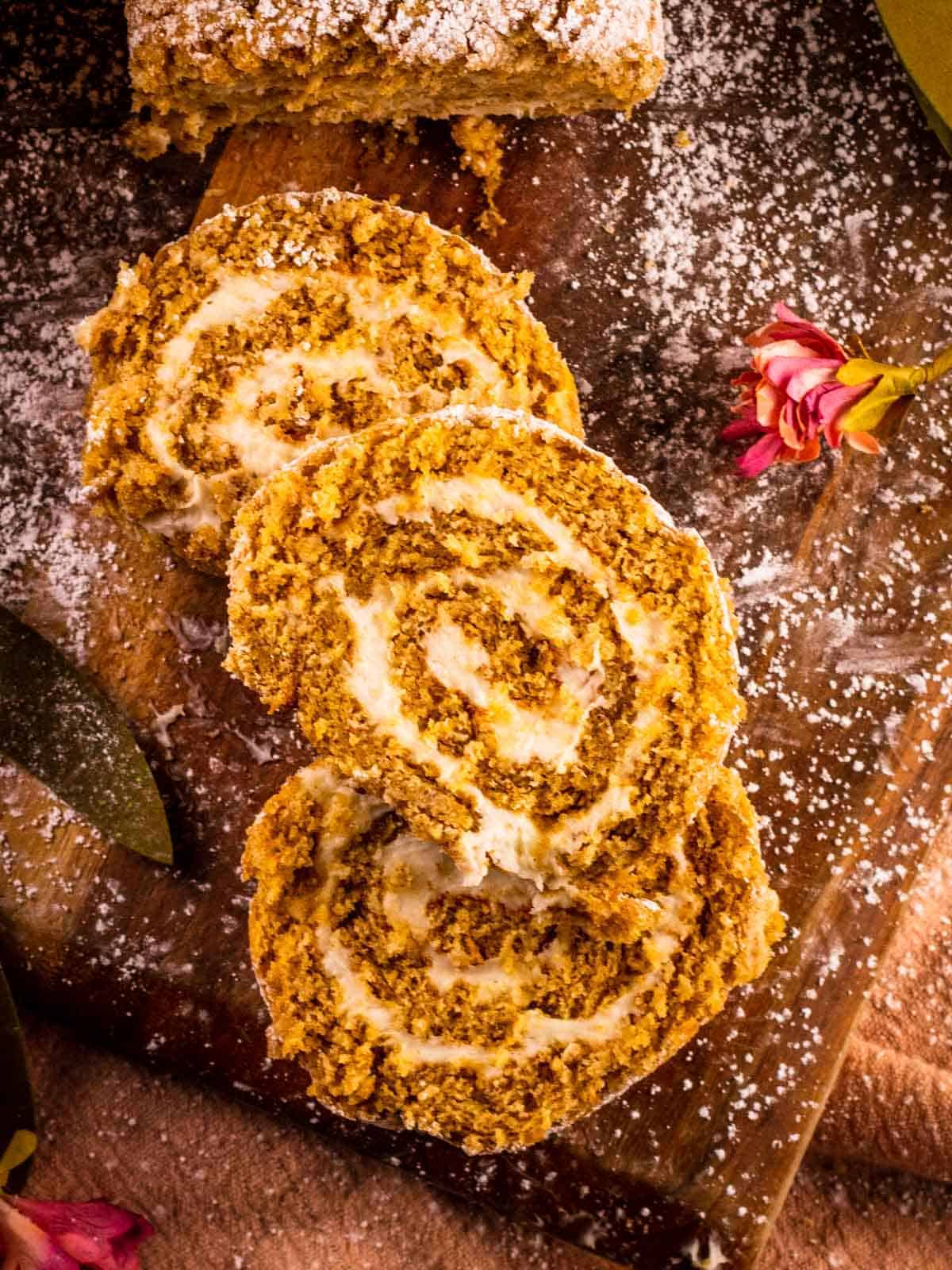 Slices of pumpkin roll cake on a wooden cutting board.