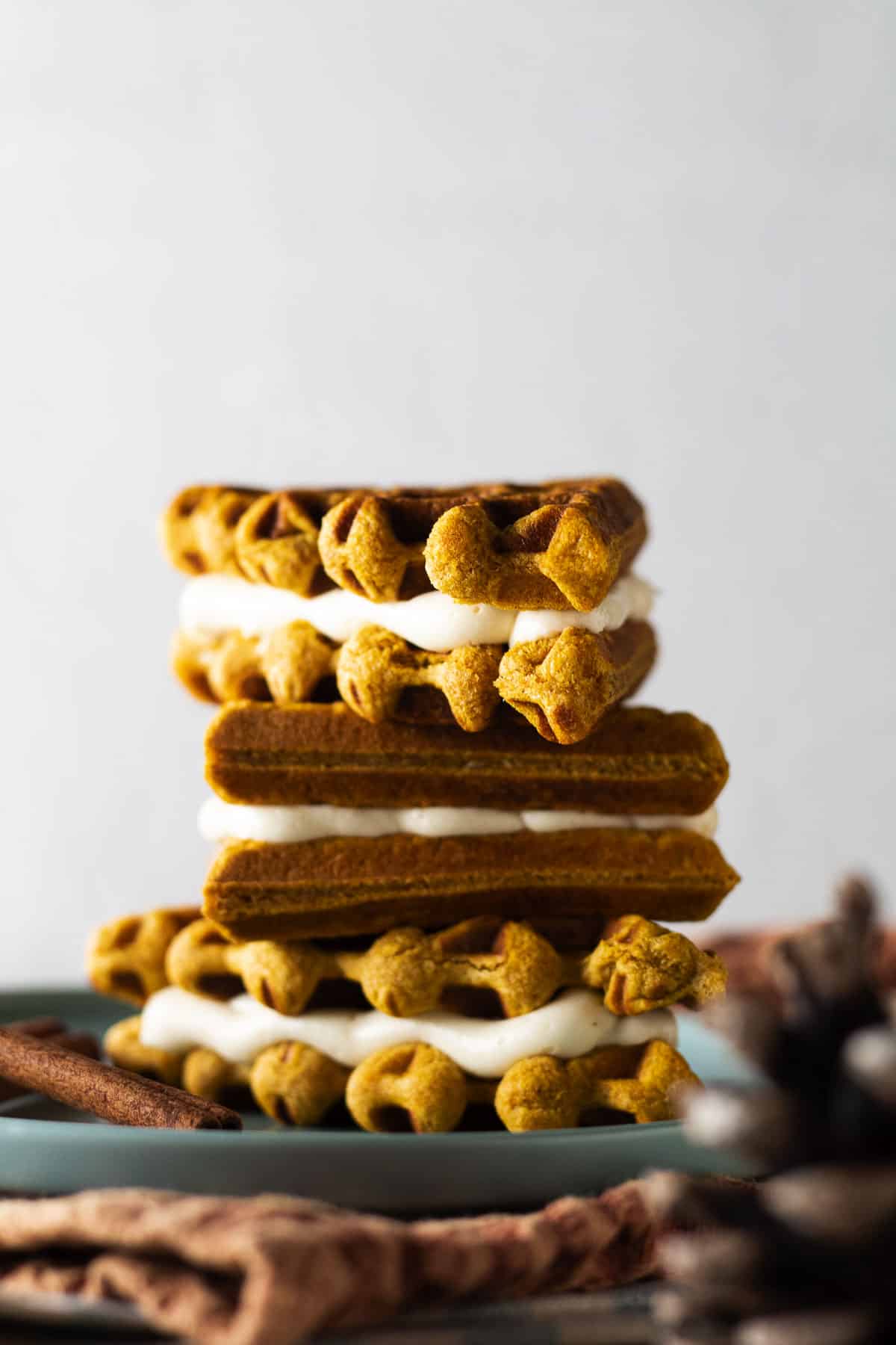 Pumpkin spice waffle whoopie pies stacked up on blue plate.