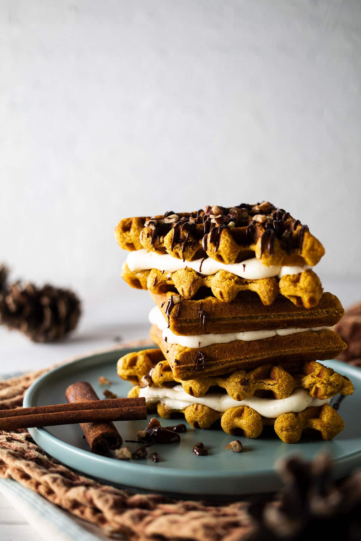 Waffle whoopie pies stacked on a blue plate with white background.