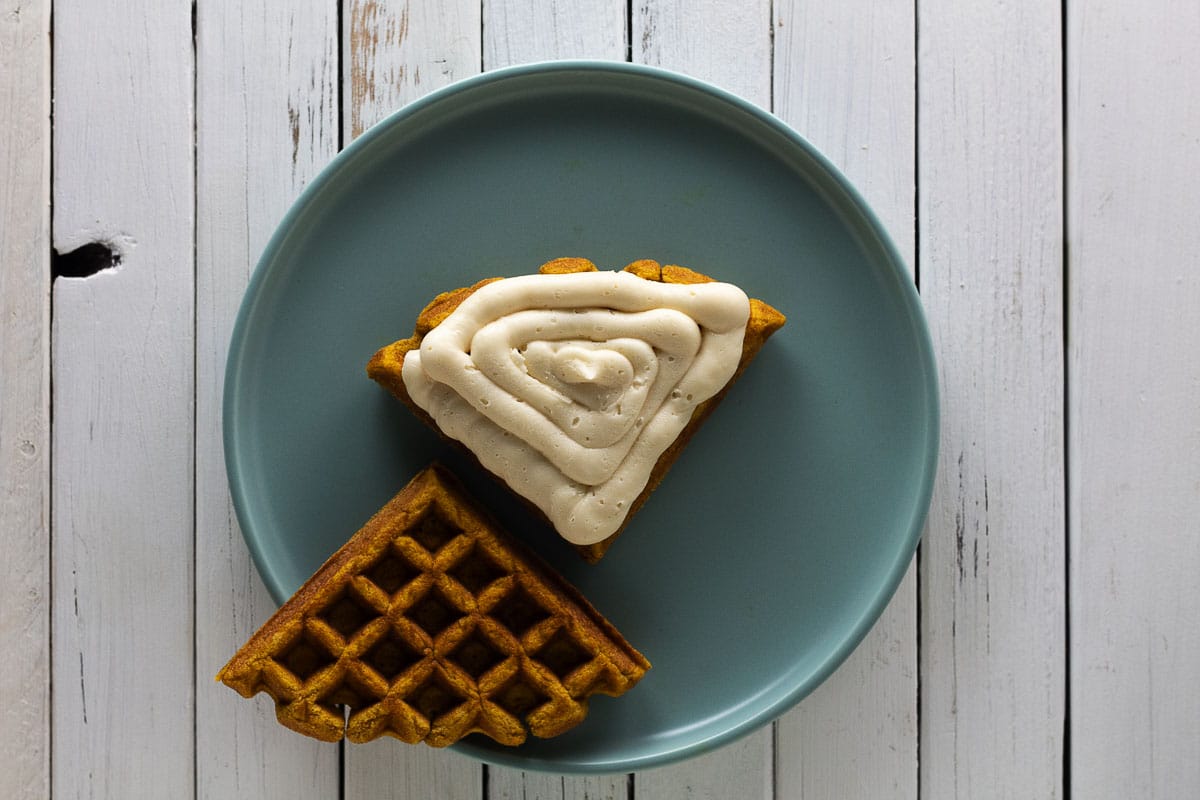 Waffle whoopie pies with frosting on blue plate with white background.