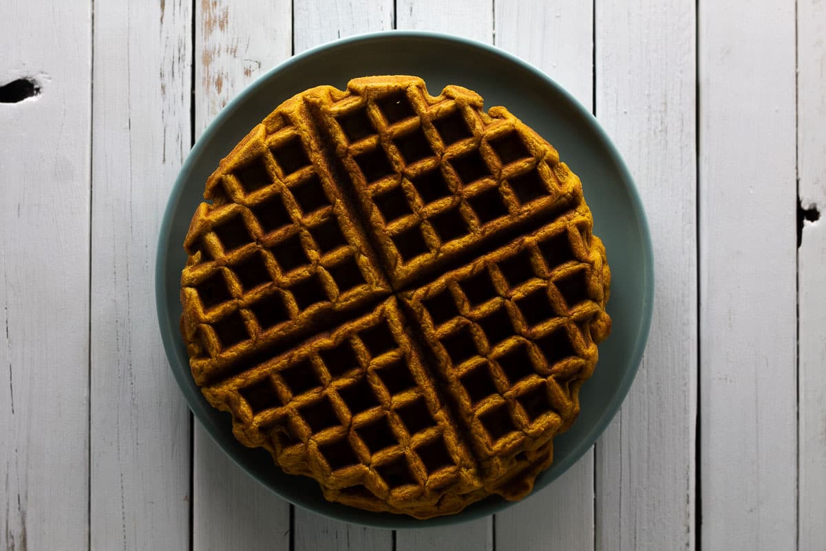 Pumpkin spice waffle on blue plate with white background.