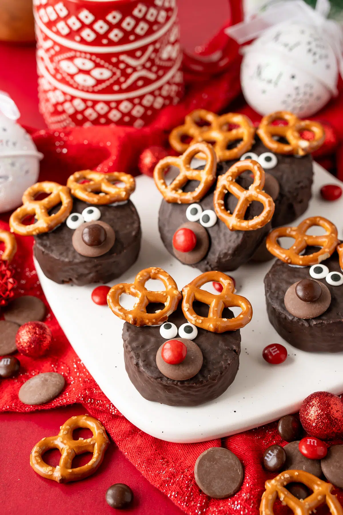 Miniature cakes fashioned to look like a reindeer with candy eyes, candy melts, m&m's, and pretzels.