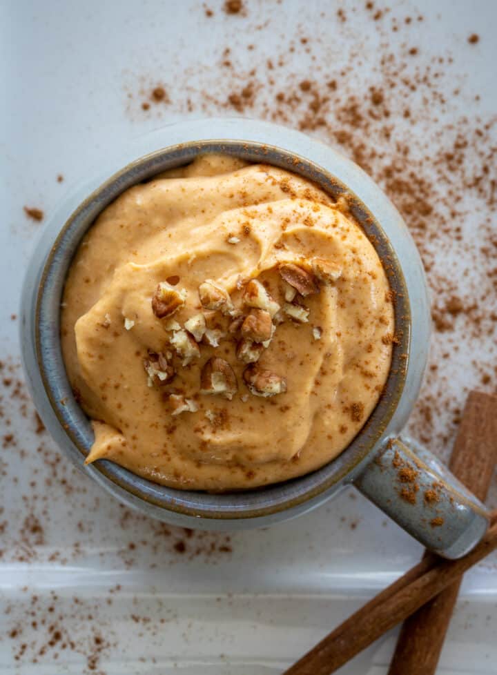 Pumpkin dip in a bowl with chopped nuts on top.