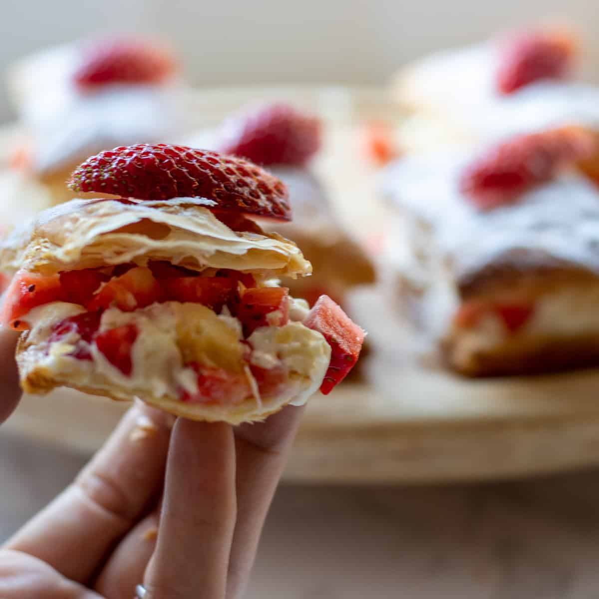 Strawberry layer dessert in hand with more in background.