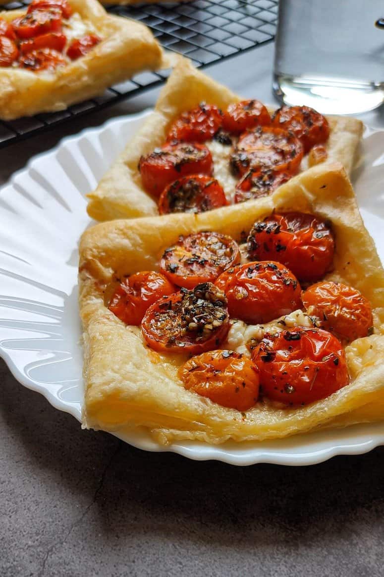 Tomato puff pastry tarts on a white plate.